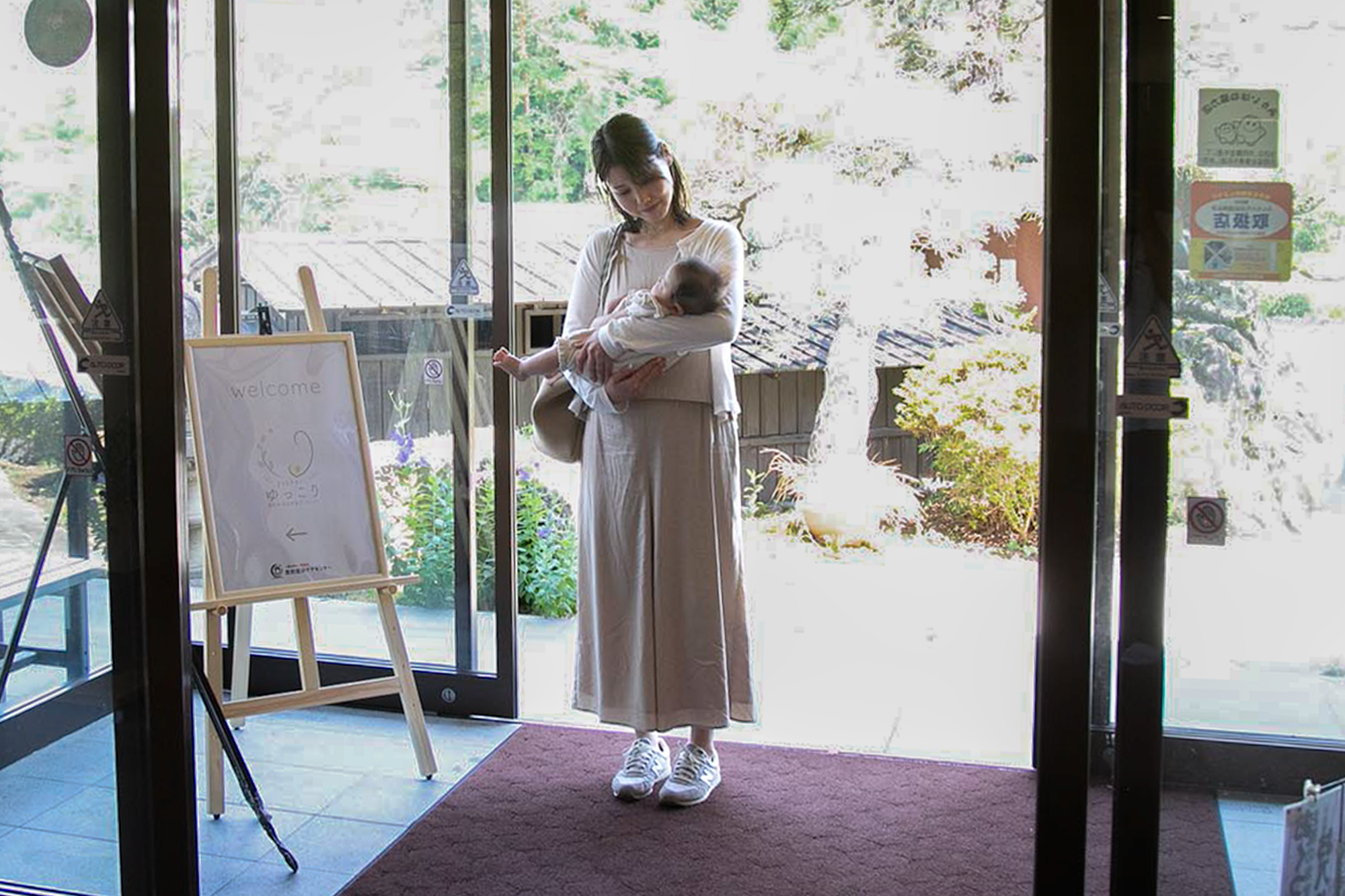 産後ケア施設の入り口に立つ母子