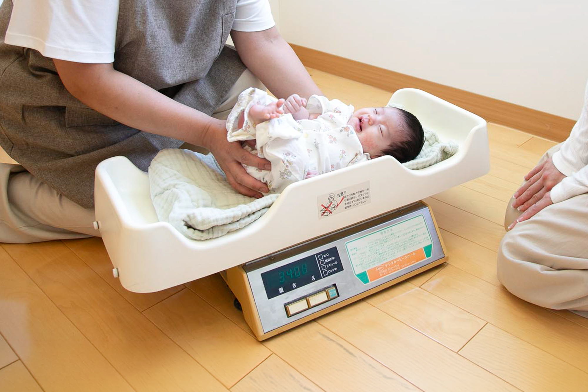 赤ちゃんを体重計に乗せる看護師