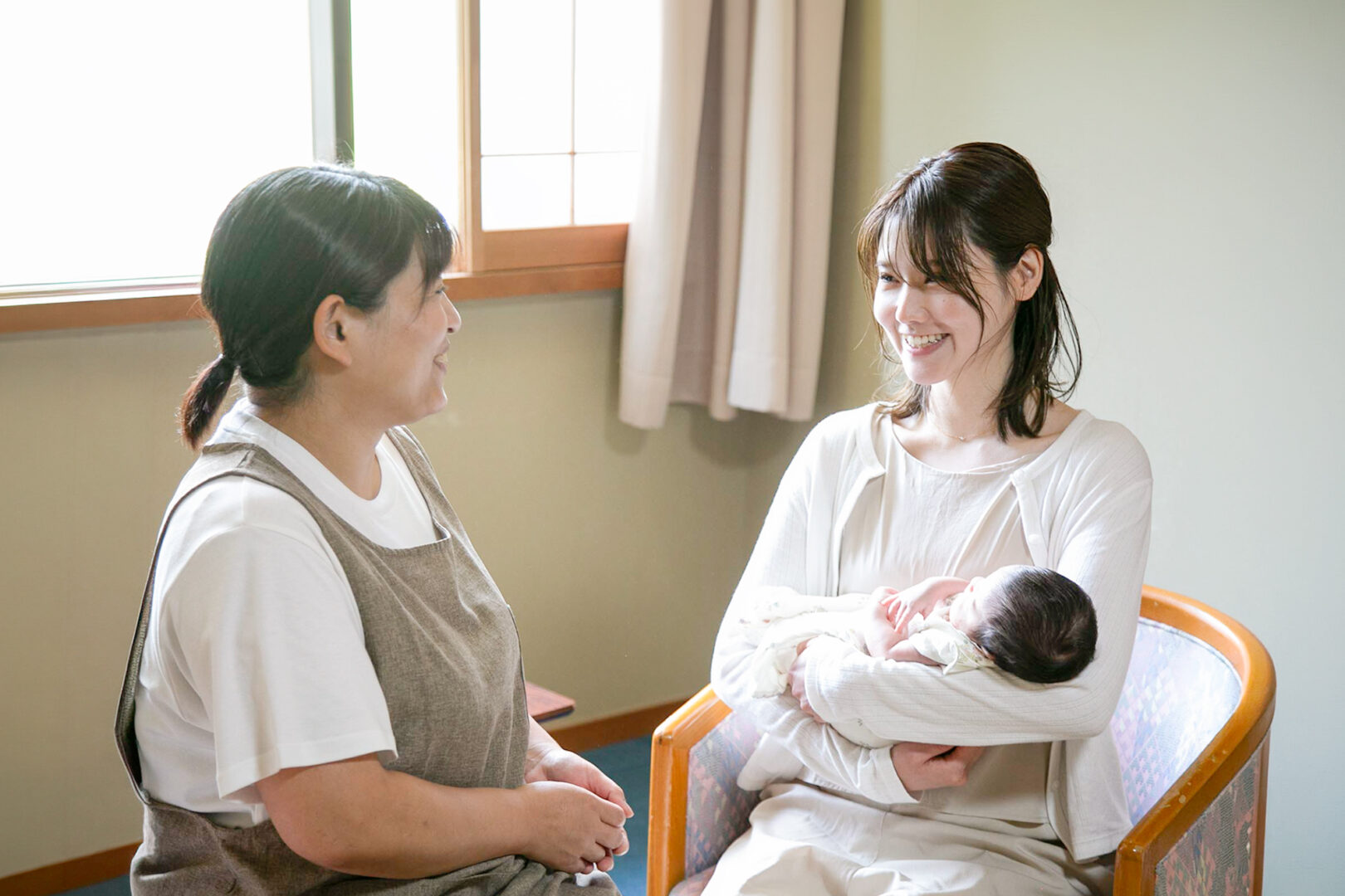 赤ちゃんを抱く妊婦さんに寄り添う看護師